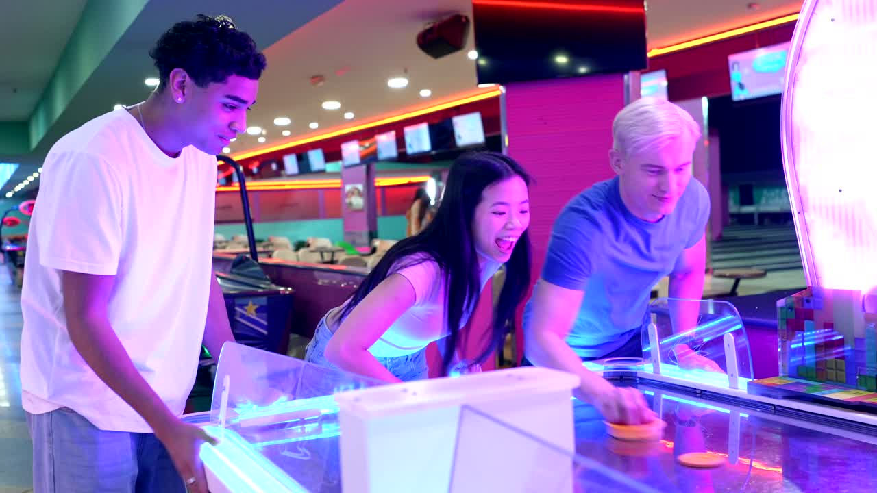 Friends playing air hockey in an arcade
