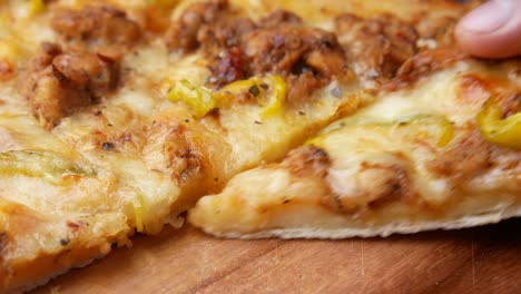 la mano recogiendo una rebanada de pizza de pollo