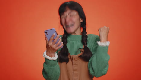 mujer feliz y emocionada usa el teléfono móvil y dice wow, sí, descubrí una gran noticia sobre una gran victoria haciendo un gesto de ganador