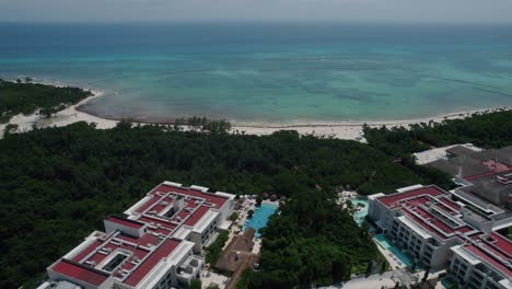 Drone-shot-of-tropical-water-pulling-back-to-reveal-a-well-furnished-resort