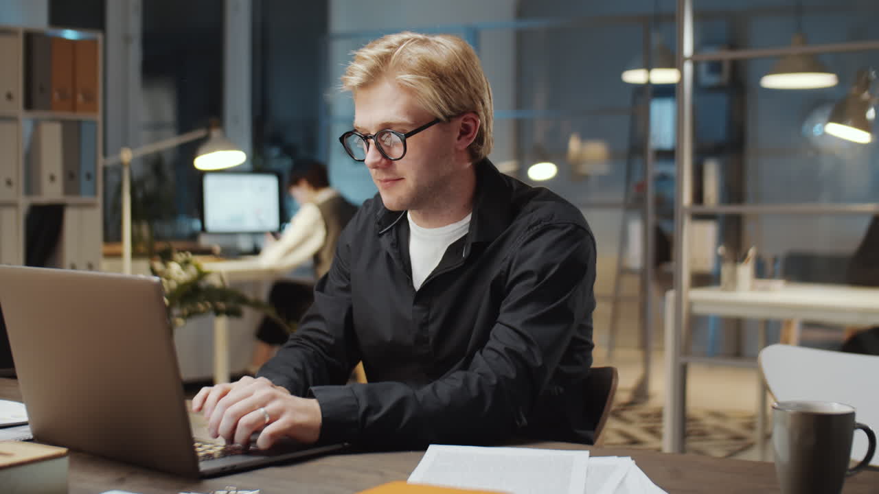 Businessman Working with Papers and Laptop during Night in Office