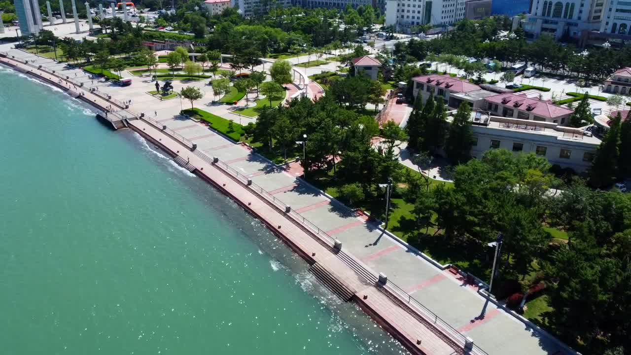 Aerial view of beautiful Xingfu seaside park with promenade pianist statue in Weihai, China