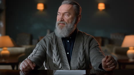 portrait greyhaired gentleman signing contract indoors. man reading documents.