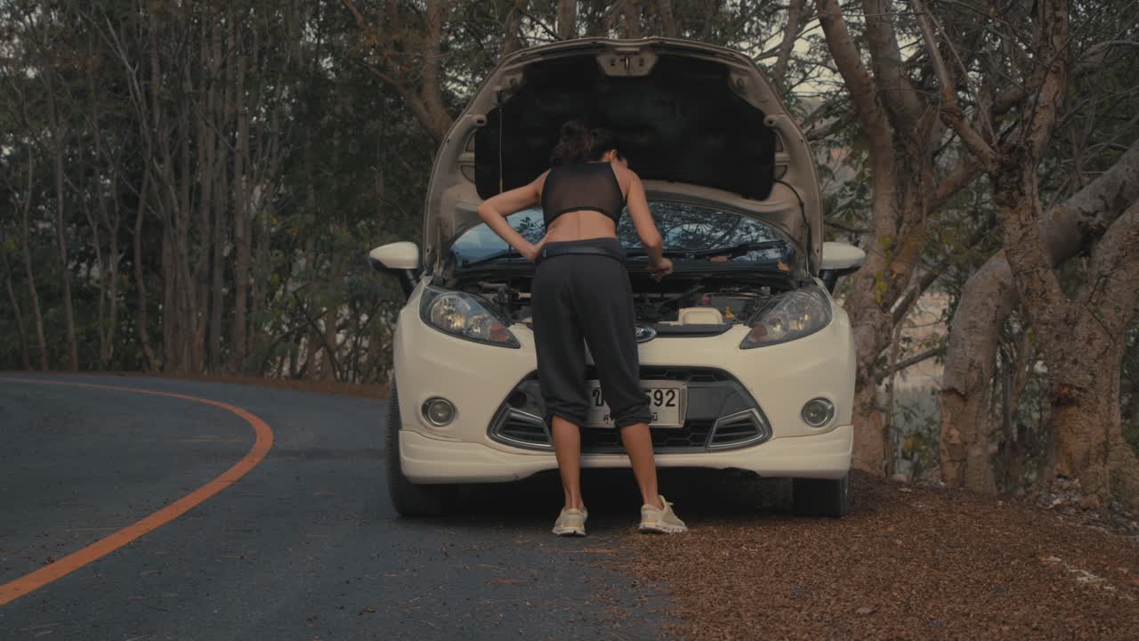 Woman Fixing a Broken Car on a Mountain Road