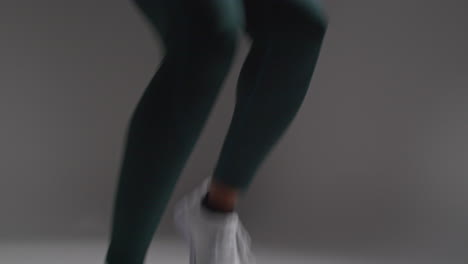 close up shot of female athlete wearing tracksuit training in gym fitness class running on the spot against plain background 3