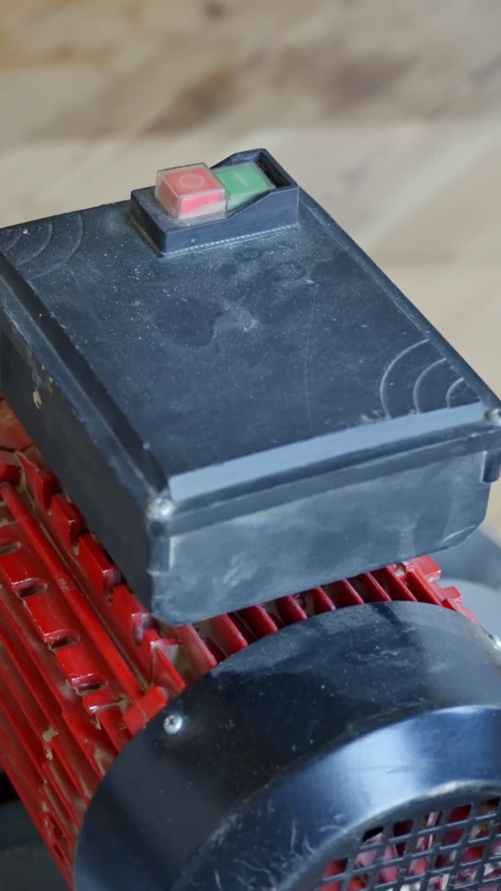 Operator pushes green button atop sander before sanding vertical pine wood floors.
