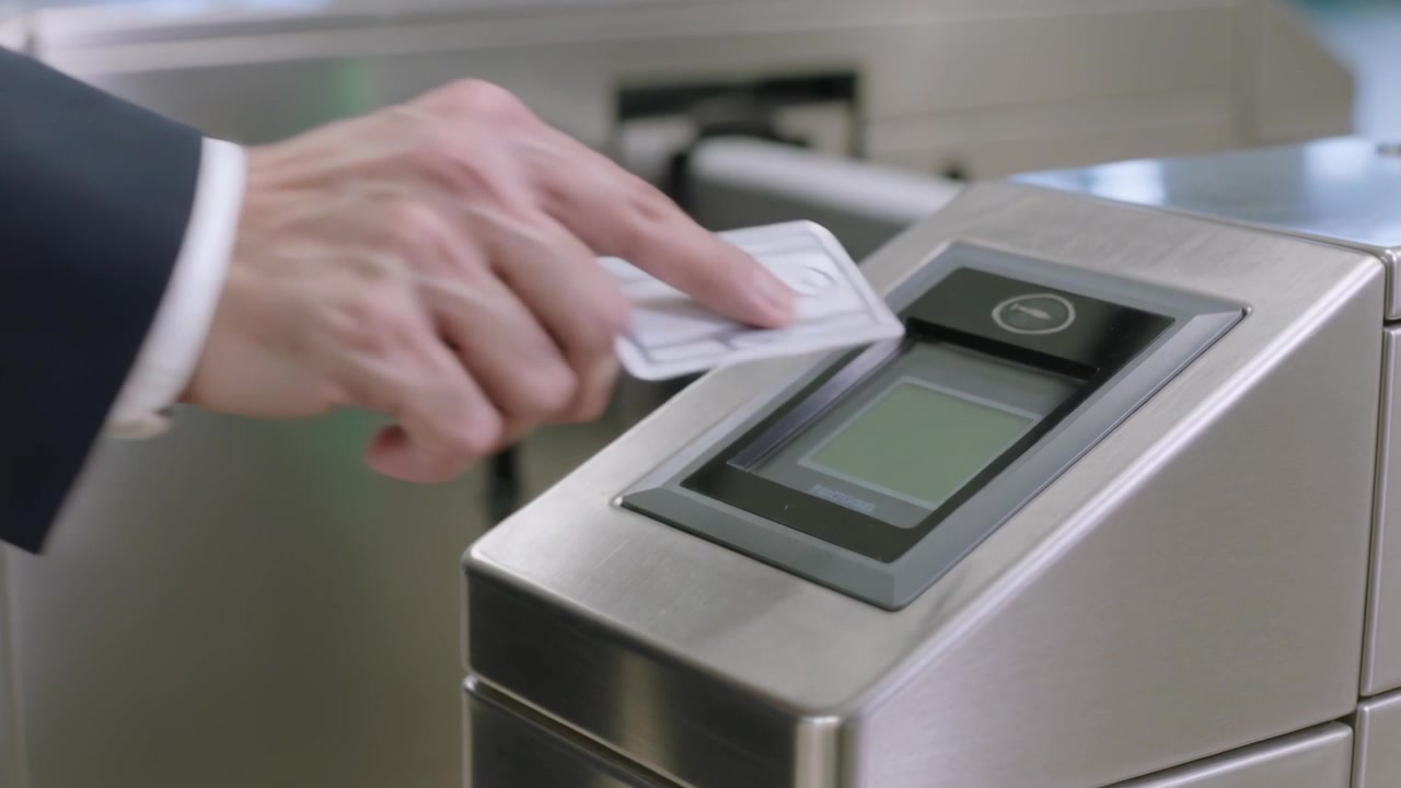 Presenting suit-clad right hand pressing access card on reader station, opening turnstile to enter