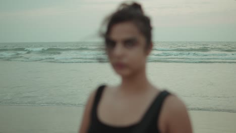 a blurred silhouette of a woman in black stands against the waves at utorda beach, south goa, during dusk