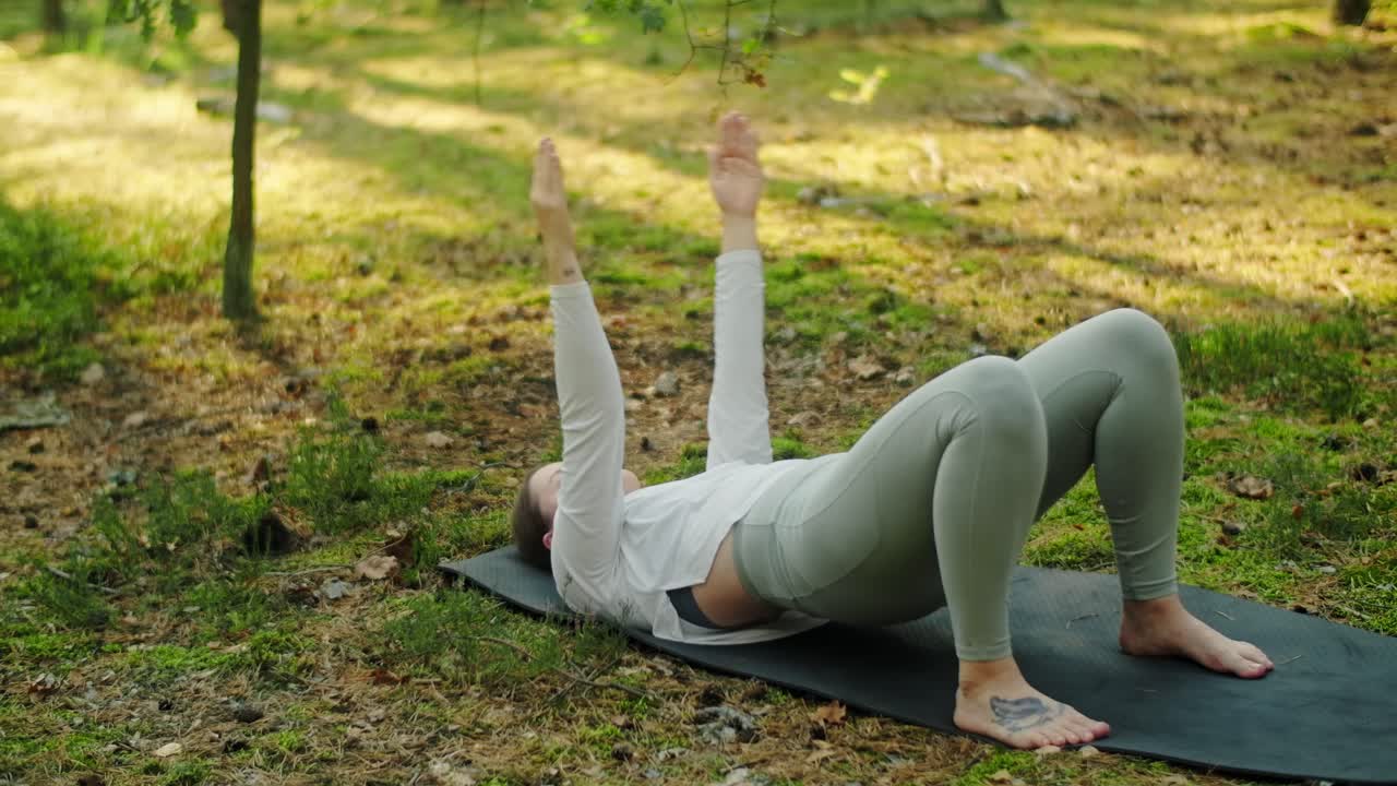 Woman doing yoga on a mat in the forest