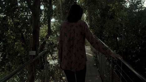 mujer joven caminando por un hermoso jardín botánico, plano general desde atrás, cámara lenta