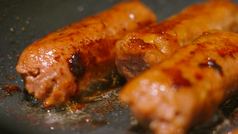 vegan sausages cooking in bubbling hot oil in frying pan as they crisp up and cook under high temperature. plant based tasty meatless food. healthier lifestyle choice