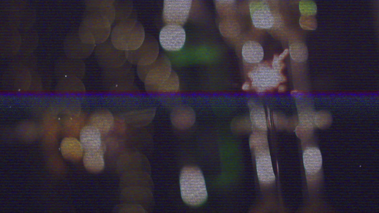 Hand holding sparkler igniting tip sending sparks fanning outward over warm bokeh for celebration