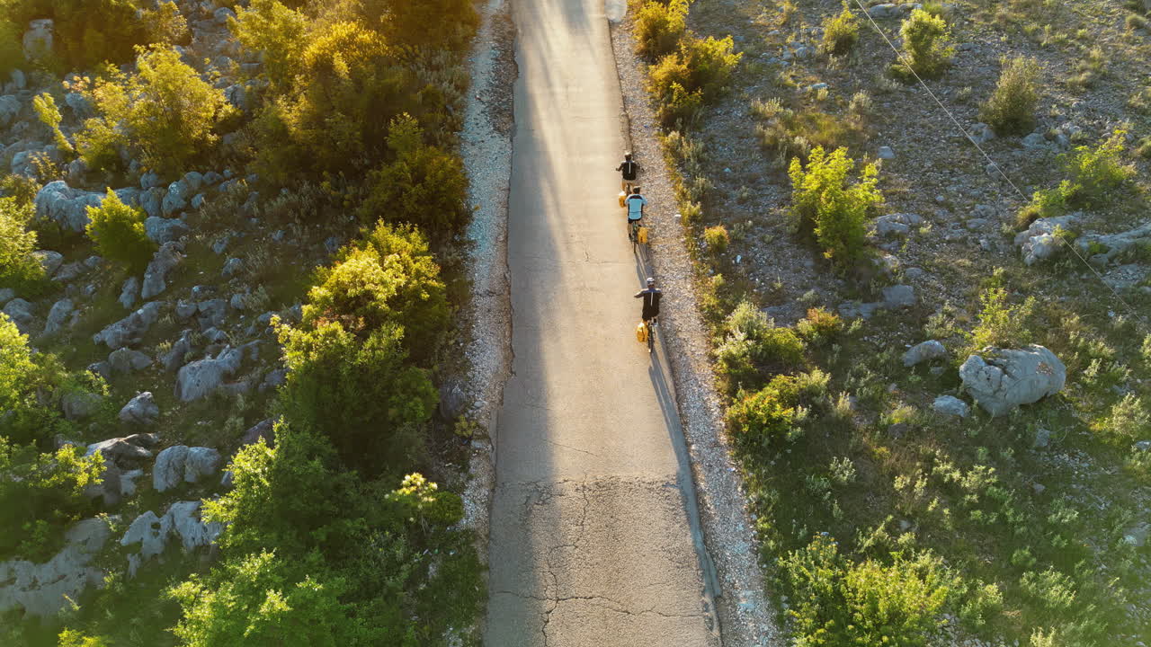 Vista aerea con drone di persone con zaini gialli che pedalano sulla strada in Albania
