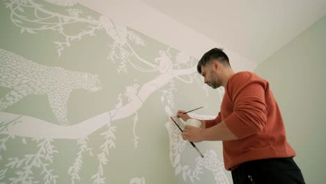 el artista está decorando las paredes con dibujos en la habitación de los niños. pintura de arte de las paredes en la casa nueva. trabajos de reparación.