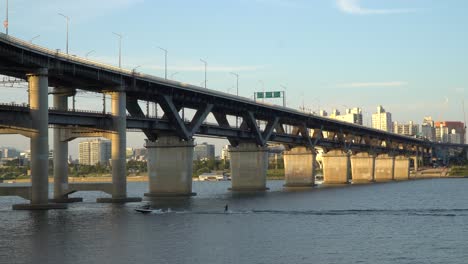 Wakeboarding-In-Han-River-Passing-By-Under-Cheongdam-Bridge-In-Seoul,-South-Korea---static-shot