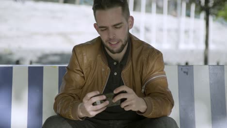 smiling young man looking at smartphone outdoor.