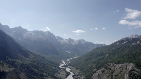 video drone frontale che avanza sulla valle di valbona e il suo fiume in secca all'altezza di llomi, si vedono piccole case e un cielo limpido