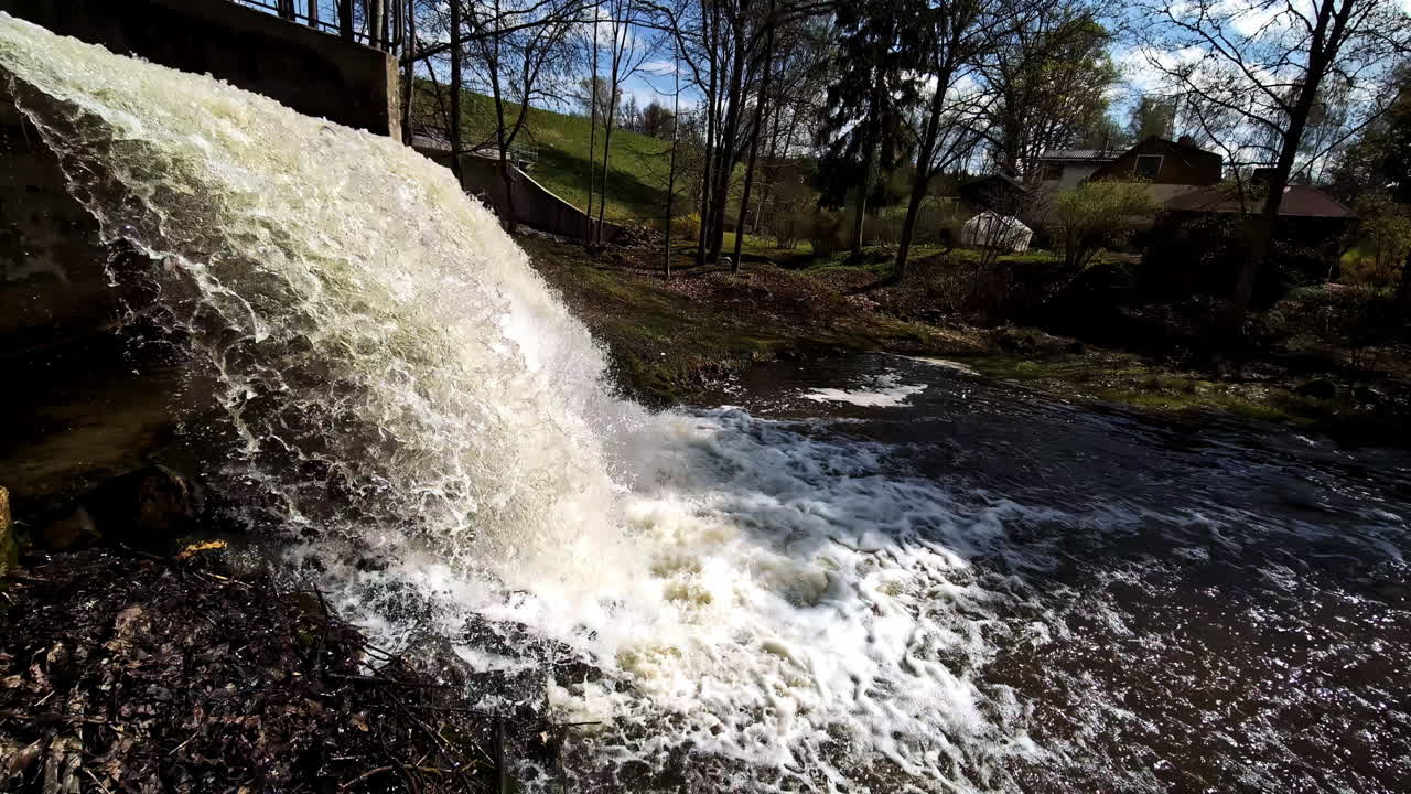 Closeup waterfall stream gushing in slow motion on sunny spring day