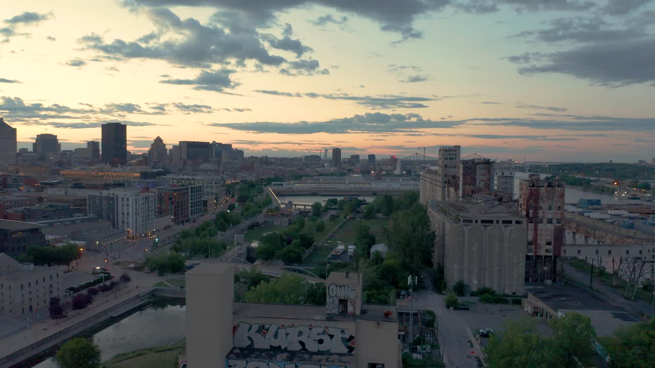 Drone flying up over an abandoned factory revealing Montreal's old port and downtown.