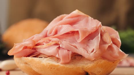 mortadella ham sandwich, traditional italian focaccia filled with thin pesto slices of mortadella, served by chef man in cafe restaurant. macro of traditional italian spanish tapas antipasti.
