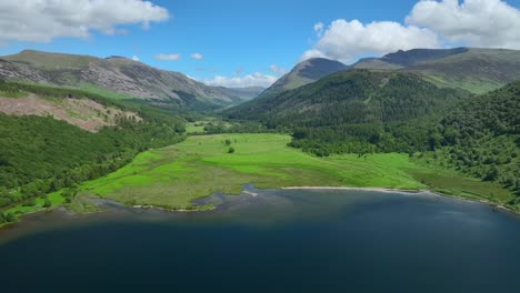 High-over-blue-lake-flying-towards-forested-mountains