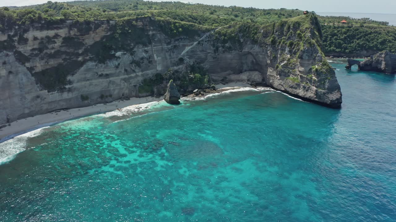 A breathtaking drone's eye view showcasing the dramatic limestone cliffs, pristine white sand, and crystal-clear turquoise waters of Diamond Beach and the surrounding coastline of Nusa Penida, Bali