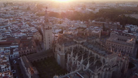 Vista-Aérea-De-La-Catedral-Gótica-Del-Casco-Antiguo-De-Sevilla,-Andalucía,-Amanecer-En-El-Punto-De-Referencia-Español,-Retroceso-En-órbita