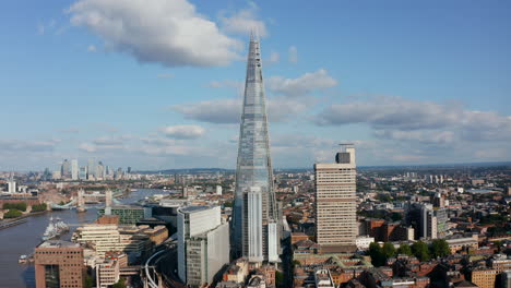 Fly-around-The-Shard-skyscraper.-Modern-futuristic-design-tall-building-with-conical-shape.-Historic-tower-bridge-and-tall-office-buildings-in-Canary-Wharf-in-background.-London,-UK