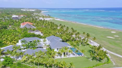 Tiro-De-Dron-Del-Paisaje-Tropical-Con-Hotel-De-Lujo-Y-Campo-De-Golf-Al-Lado-De-La-Playa-Del-Mar-Caribe---Hermosa-Costa-De-República-Dominicana-Durante-La-Luz-Del-Sol