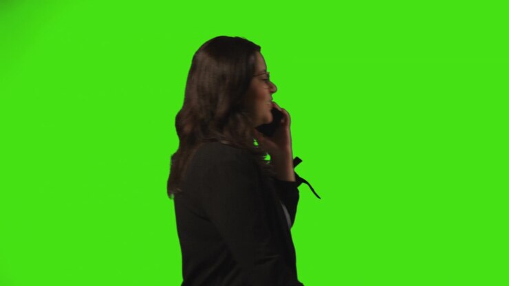 Side View Shot Of Businesswoman Talking On Mobile Phone Walking Across Frame Against Green Screen 2