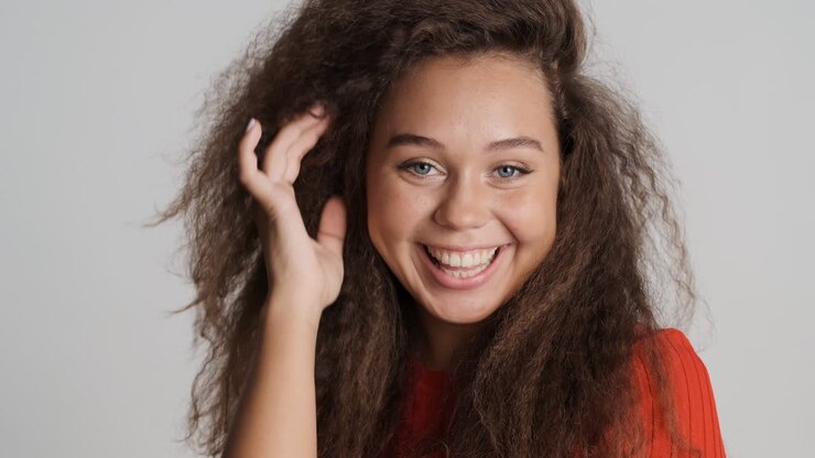 Donna caucasica con i capelli ricci che sorride.