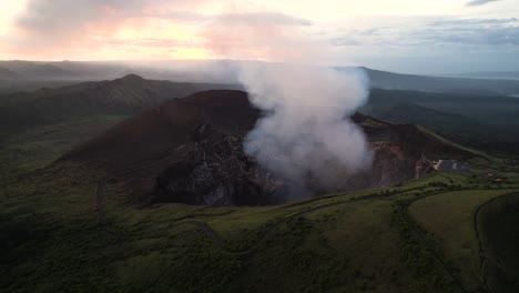 aerial shot over a crater full of steam from erupting volcano in central america