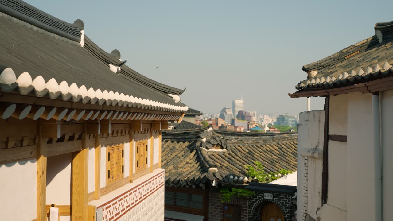 Bukchon Hanok Village’s tiled rooftops and wooden architecture in Jongno-gu, Seoul, with city skyline in the distance
