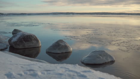 Dramatic-Sunrise-View-By-The-River-With-Rocks-Covered-With-Ice-During-Winter-Season-In-Finland