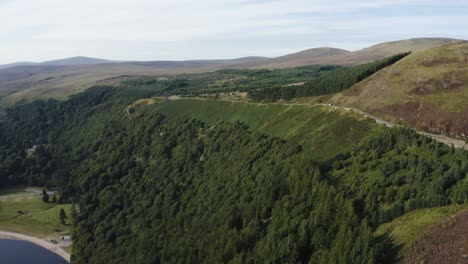 aerial view of an empty long, winding mountain road in the wicklow mountains with lough tay in the view on a sunny day