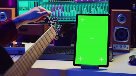 ingeniero de audio practica afinando su guitarra acústica en su estudio casero