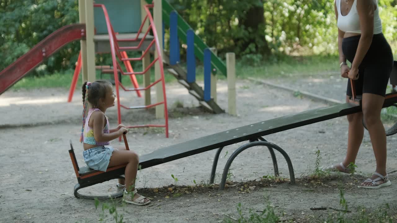 madre y hija embarazadas jugando en el columpio en el parque