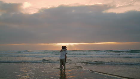 married lovers having fun sunbeams coastline. man woman spinning beach vertical