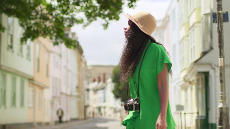 female tourist with camera on vacation in oxford uk exploring city walking along holywell street towards camera