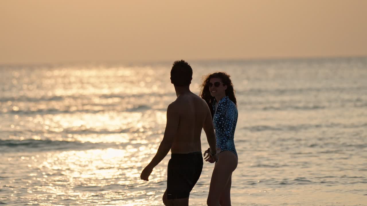 A loving pair stands barefoot on the soft white sands of Dhigurah as the sun sinks toward the horizon.