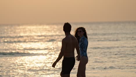 a loving pair stands barefoot on the soft white sands of dhigurah as the sun sinks toward the horizon.