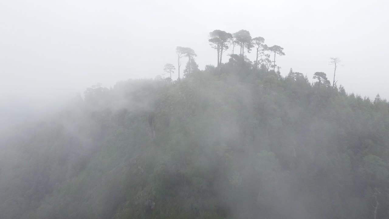 안개와 구름으로 둘러싸인 산꼭대기에 있는 작은 예배당의 공중 드론 전망