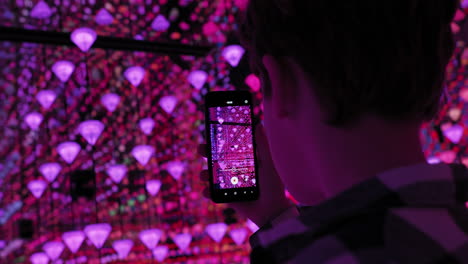 boy taking a picture of a colorful diamond light installation