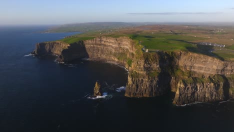 Cliffs of Moher, County Clare, Ireland, May 2025. Drone slowly pulls back over, along wild Atlantic way, Irish coastline at sunset, rugged seascape, Atlantic ocean waves crash scenic sea cliffs.