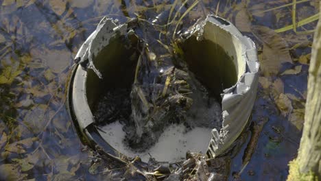 Close-up-shot-of-river-little-ouse-water-flowing-into-an-old,-crumbling-concrete-pit-polluting-the-environment