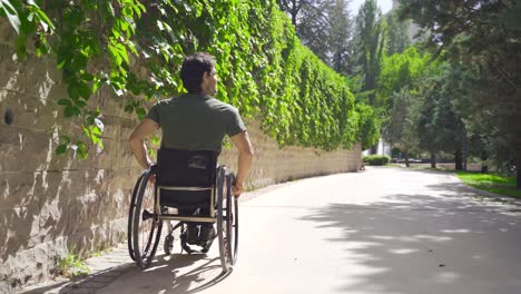 un joven con las piernas paralizadas en silla de ruedas camina solo por las calles de la ciudad.