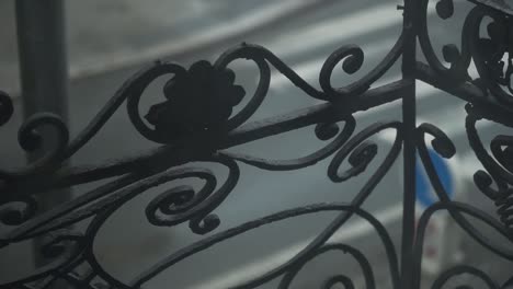 old school metal balcony railing with decoration - spirals and leaves, cars in a background