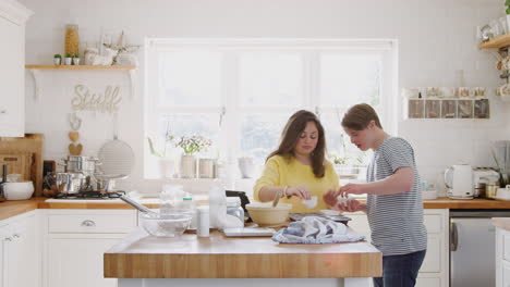 Young-Downs-Syndrome-Couple-Putting-Paper-Cupcake-Cases-Into-Tray-In-Kitchen-At-Home