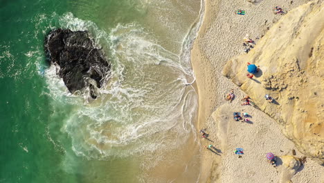 Waves-Crashing-On-Outcrop-Near-Windansea-Beach-With-People-Relaxing-On-A-Sunny-Day-In-La-Jolla,-California,-USA