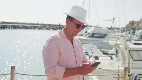 Side-view-of-a-Caucasian-man-using-his-phone-harbor-side